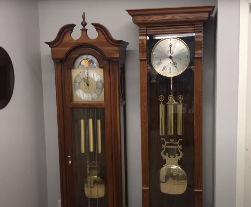 two different Howard Miller grandfather clocks standing against the wall