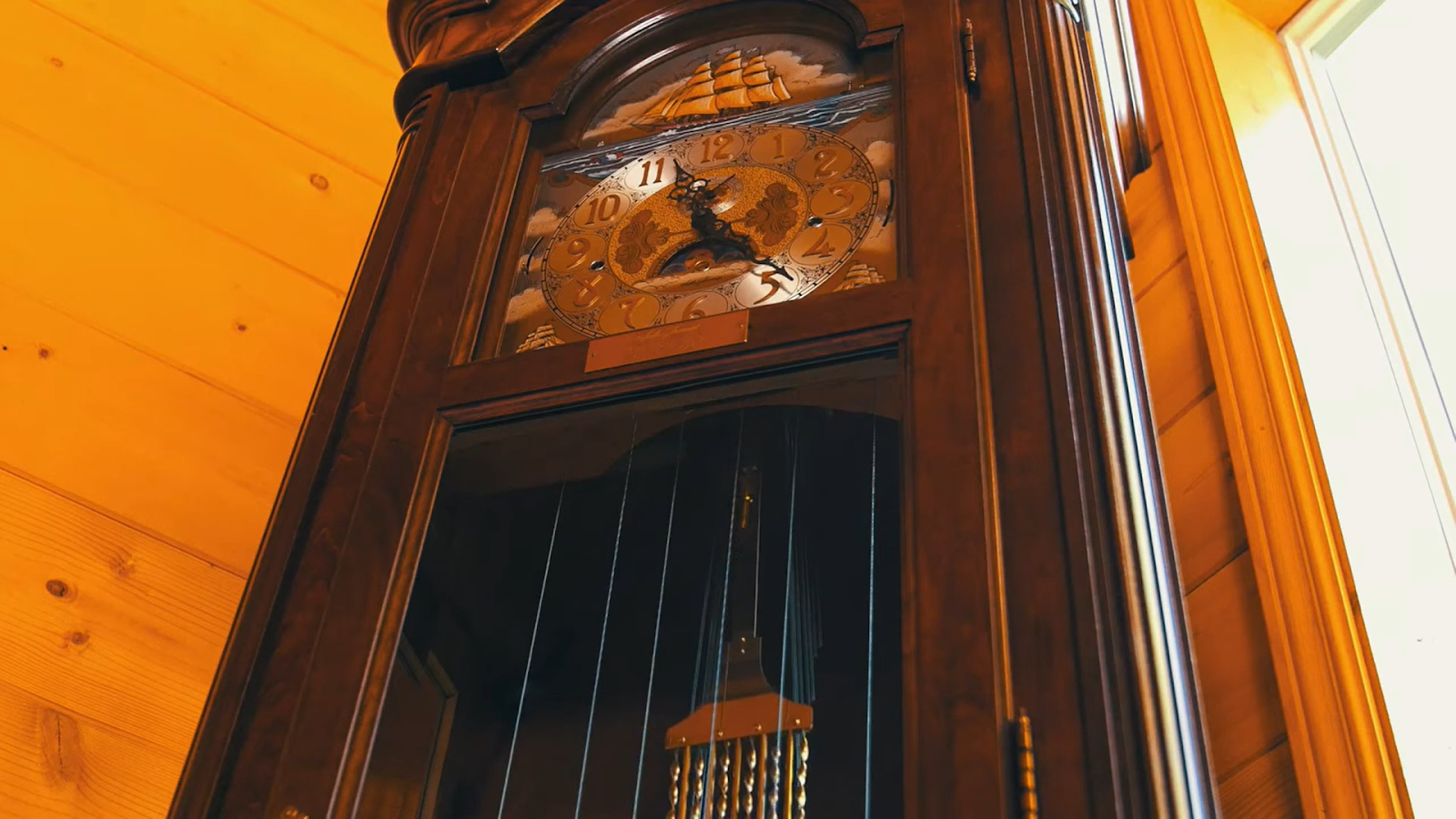 A grand wooden grandfather clock with ornate gold detailing stands